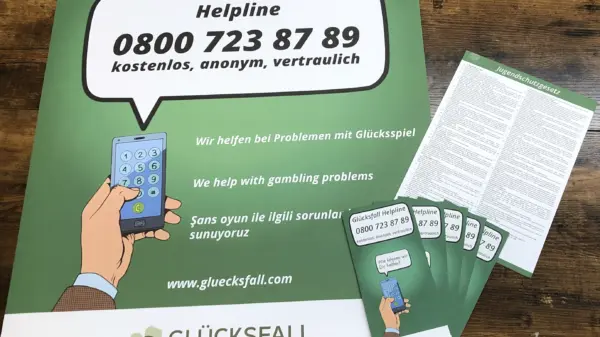 Spielerschutz-Material mit Plakat zur Helpline und mehreren Broschüren – Informationen zur Hilfe bei Glücksspielproblemen in mehreren Sprachen.