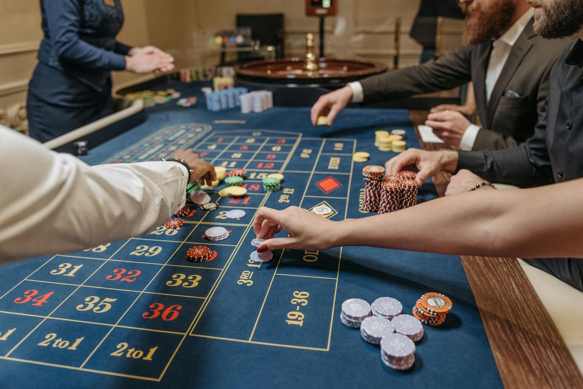 Personen setzen Jetons an einem Roulette Tisch im Casino