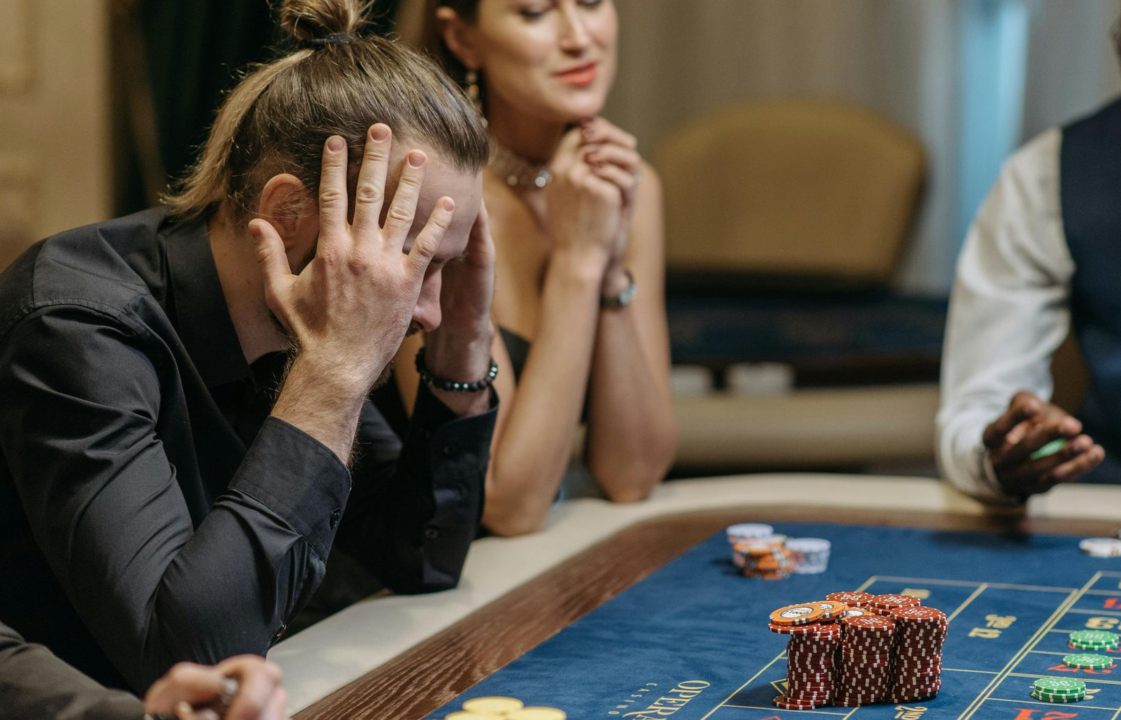 Person am Roulettetisch legt die Hände an den Kopf während Jetons auf dem Tisch liegen