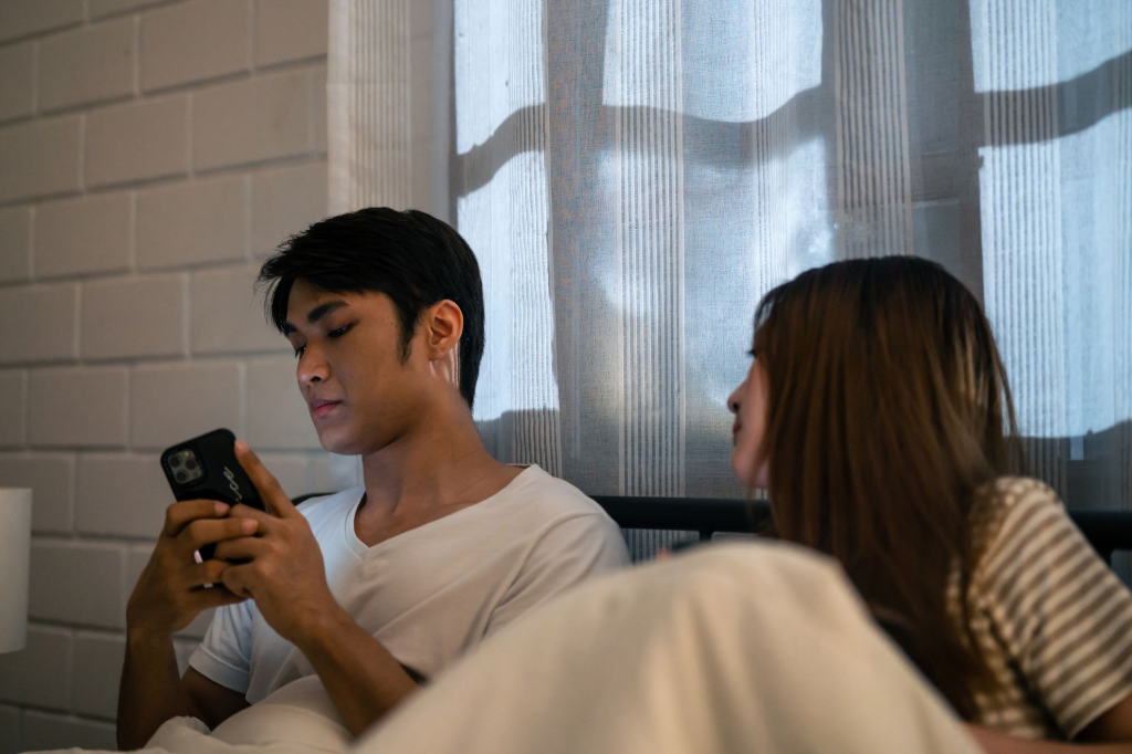 Person nutzt ein Smartphone während eine weitere Person daneben sitzt