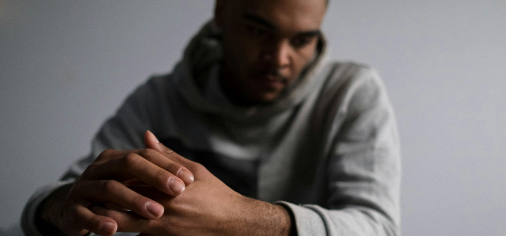 Person sitzt mit verschränkten Händen in nachdenklicher Haltung